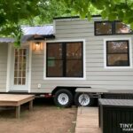 Adirondack tiny house with awning and large windows for cozy small space living.