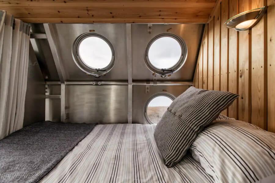 Cozy tiny house bedroom featuring unique dragonfly eye windows in Scotland.