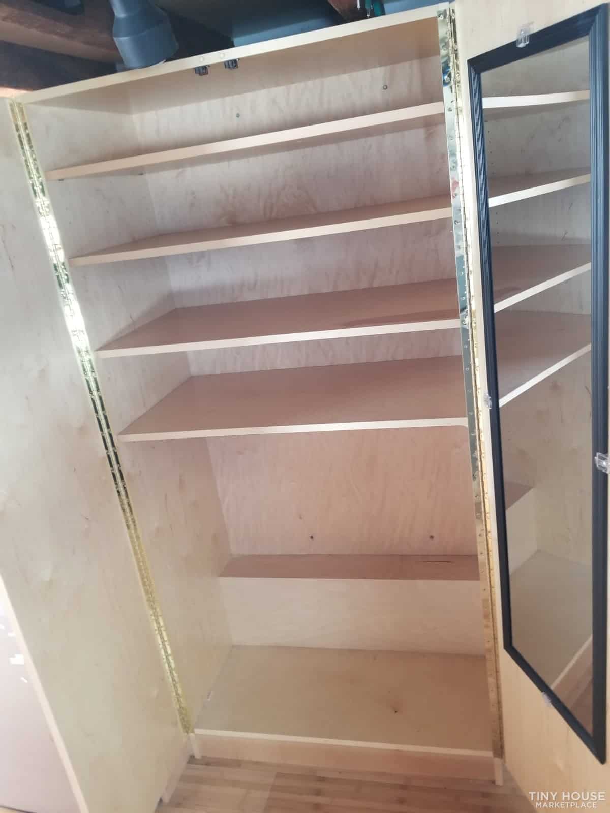 Interior view of a wooden storage cabinet with multiple shelves and a glass door.