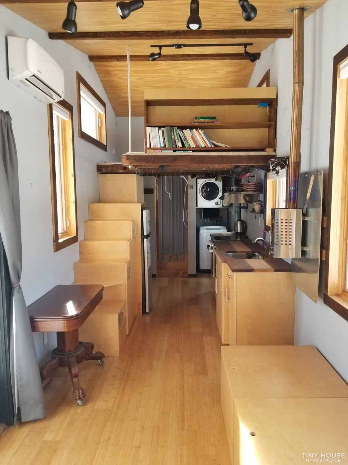 Compact tiny house interior with wooden accents and loft area for efficient small space living.