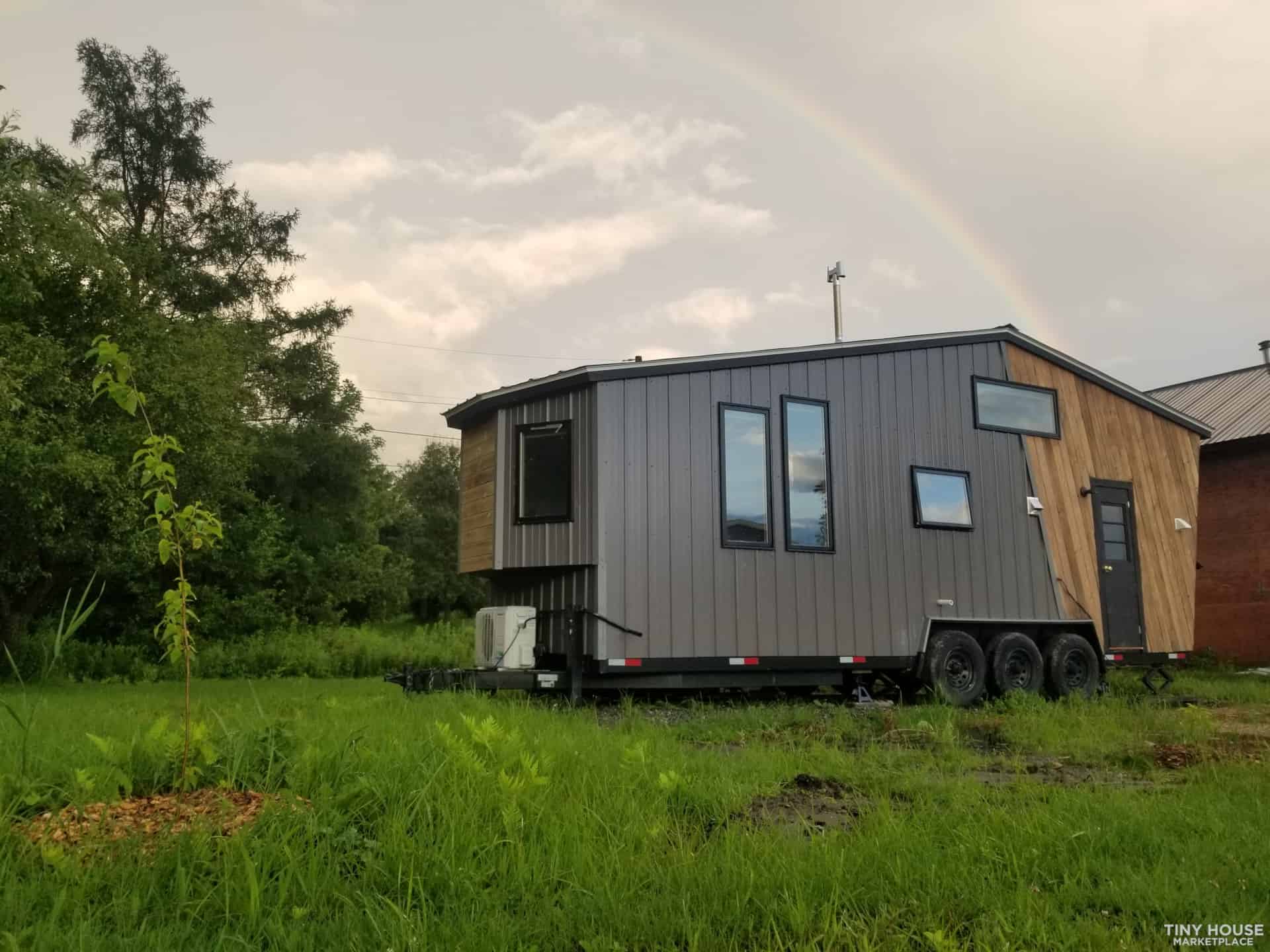 Modern tiny house on wheels with sleek black exterior and large windows.