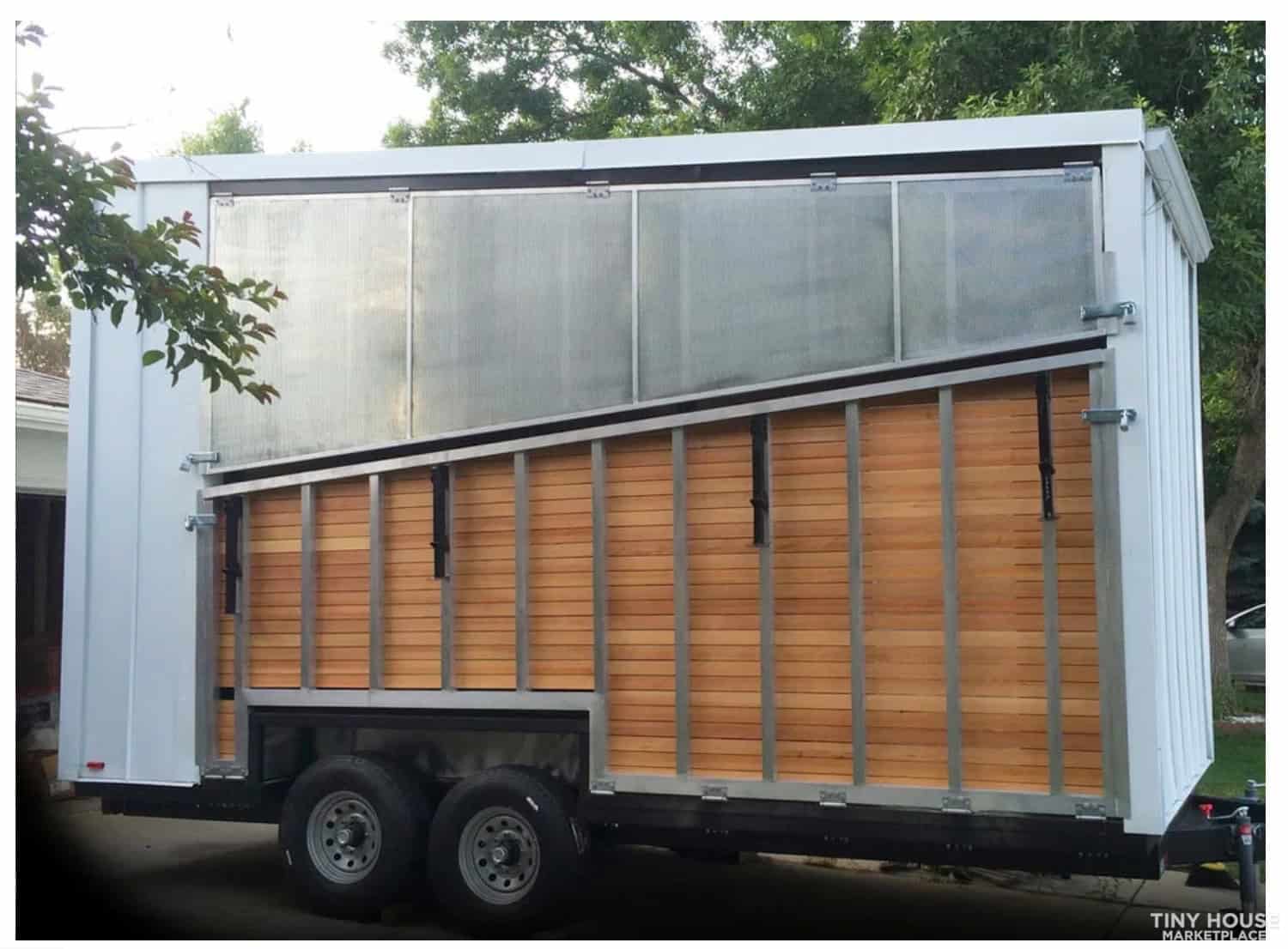 Tiny house on wheels with sleek exterior and large windows for a compact, mobile living space.