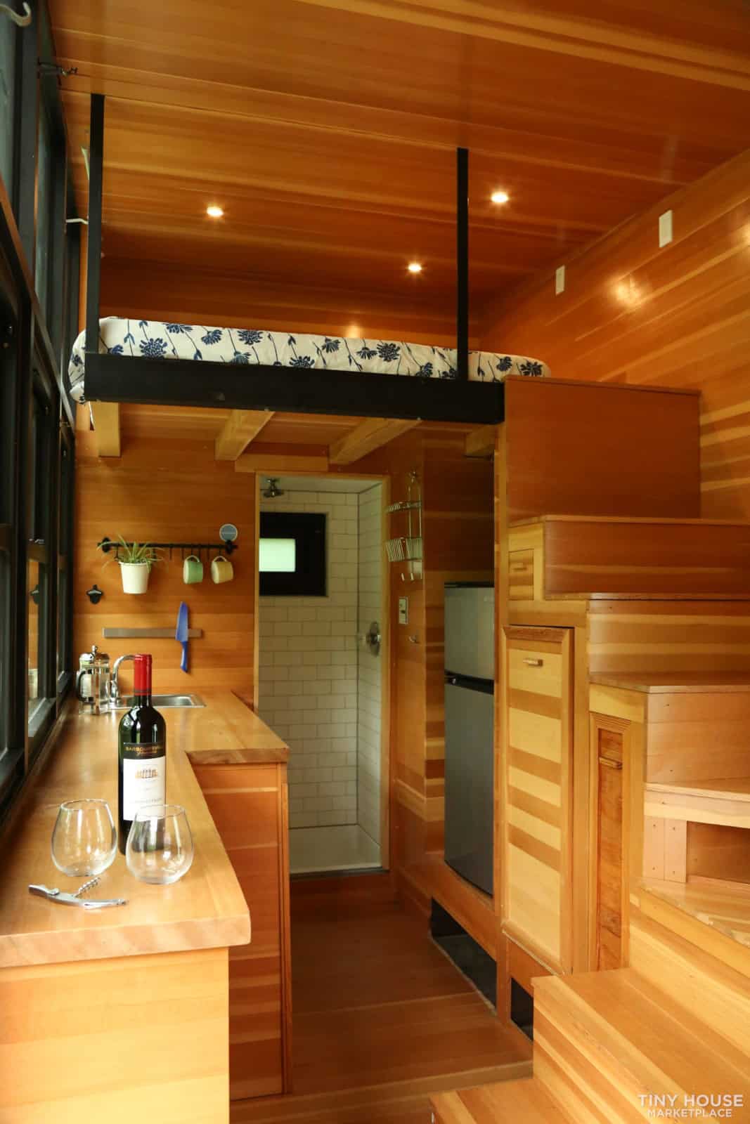Compact tiny house kitchen with warm wood finishes and efficient space utilization.