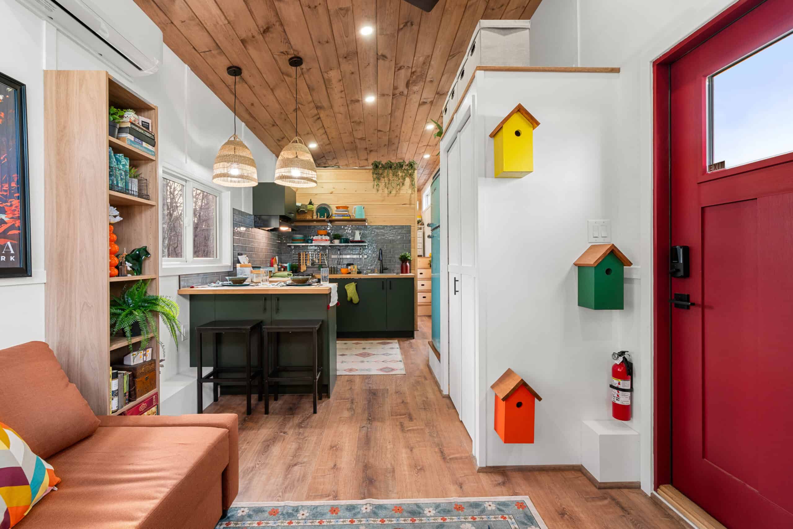 The interior of The Knoll looking from the entry toward the green kitchen, with decorative birdhouses on the wall and a wood ceiling