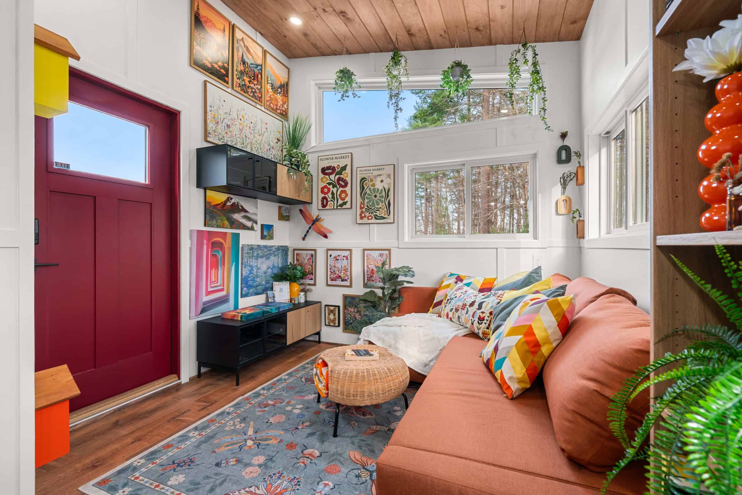 The Knoll living room with the red entry door, orange sofa, and a colorful gallery wall