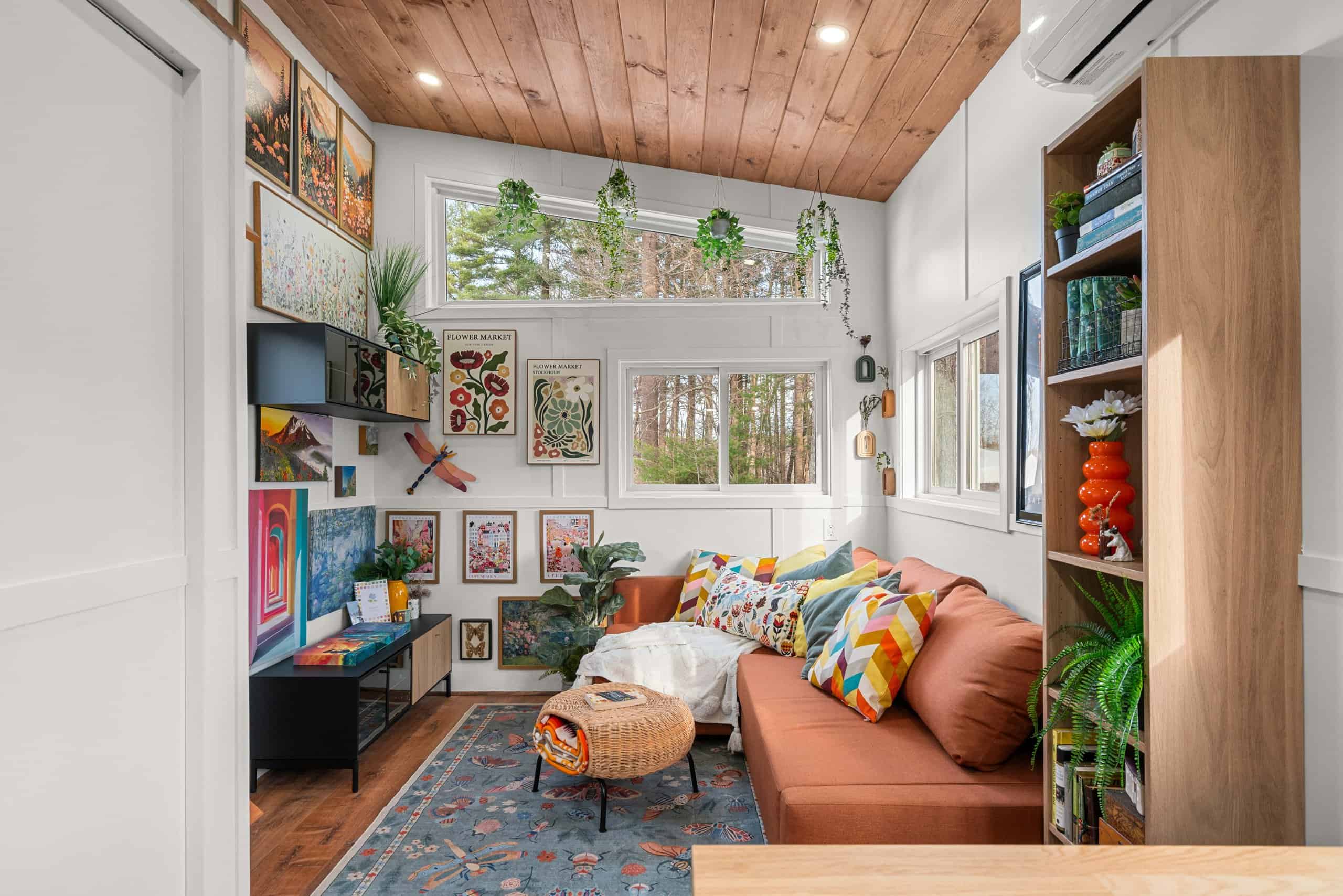 The Knoll's living room seen from the kitchen, with the orange sleeper sofa, gallery wall, and a tall built-in bookshelf