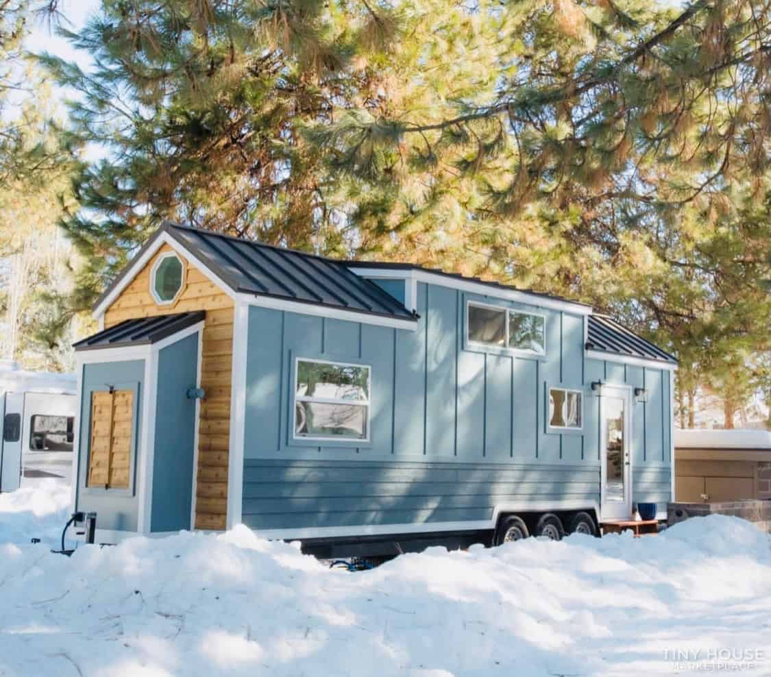 Tiny House with Blue Exterior and Snowy Landscape