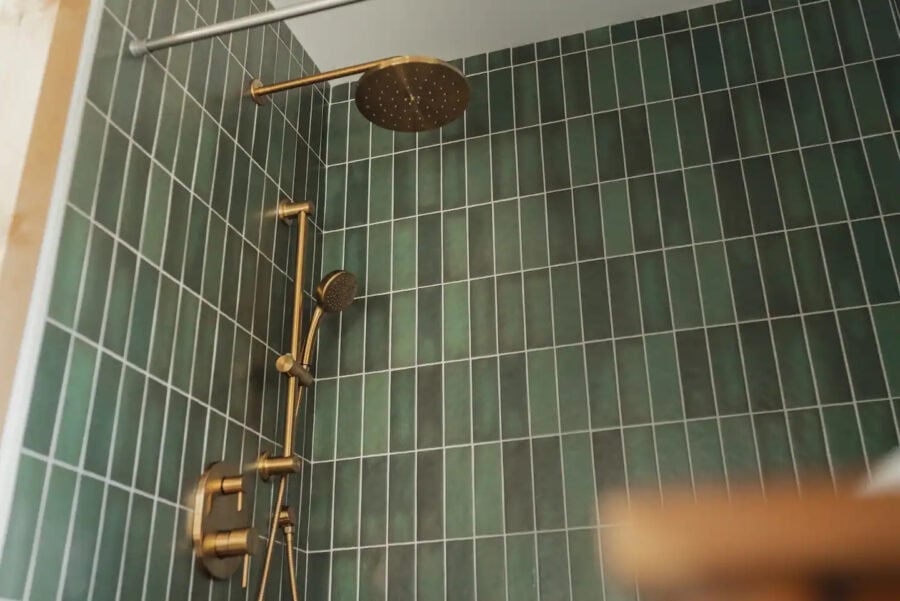 Shower with gold fixtures in a compact, modern tiny house bathroom.