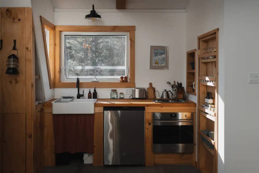 Compact tiny house kitchen with wooden accents and modern appliances in Quebec.