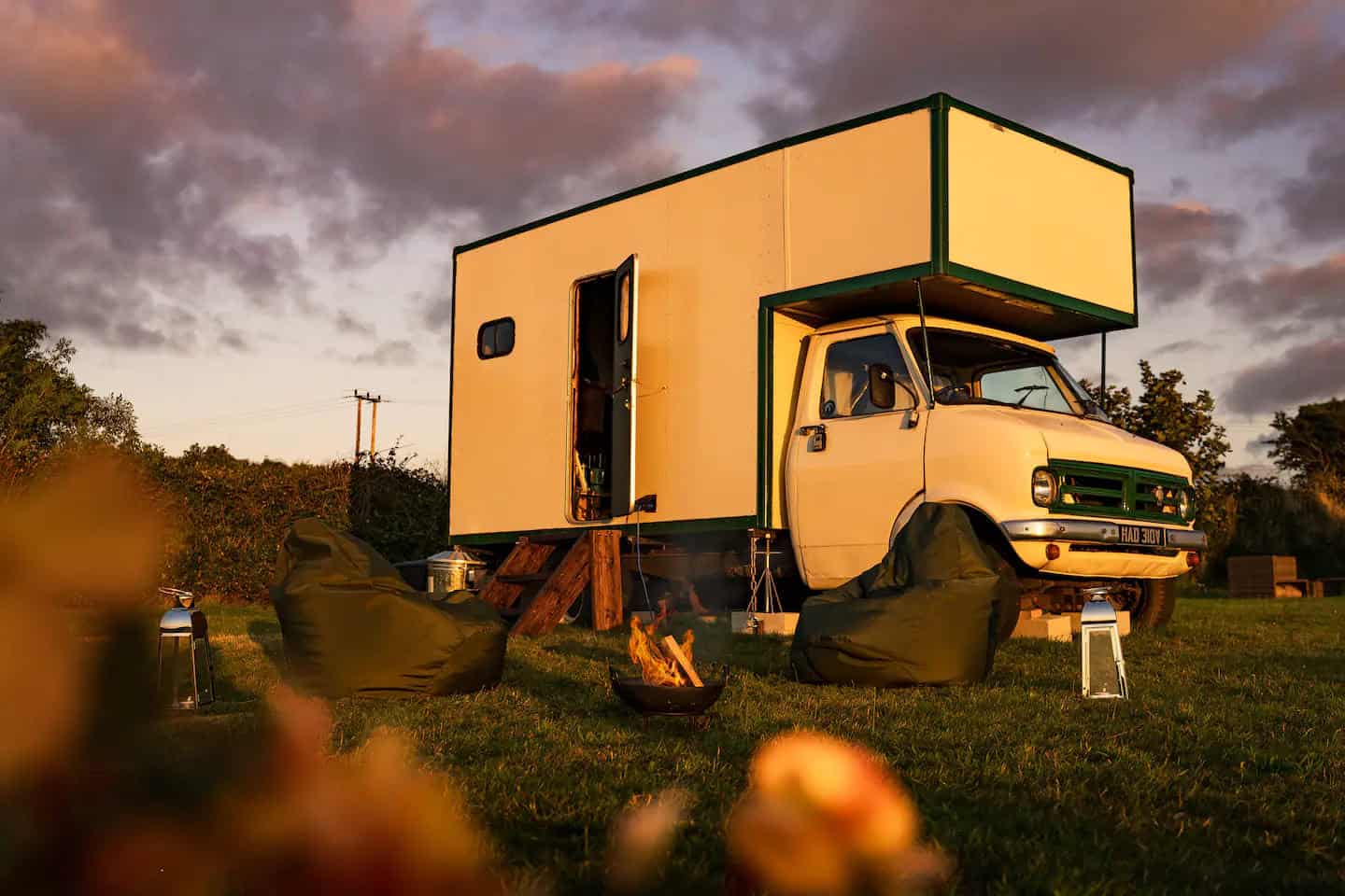1979 Bedford CF van converted into a 1970s-style cabin, parked on a Cornwall meadow at sunset with a fire pit