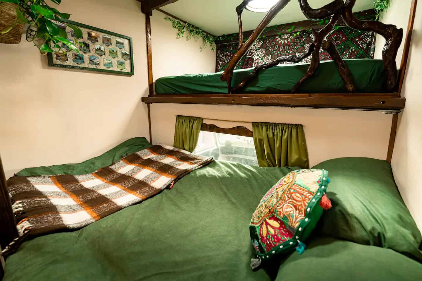 Two sleeping areas in the van: a made-up lower bed and the upper nook with green bedding and a tapestry