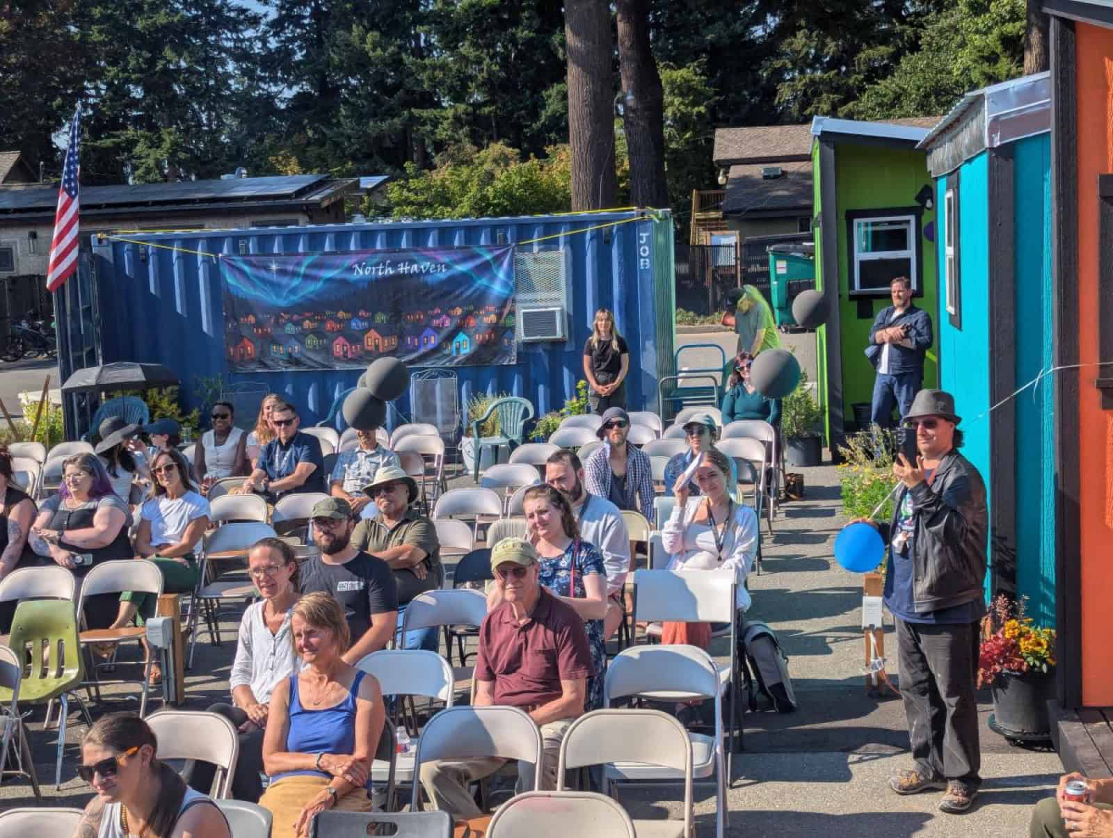 Residents and neighbors gathered in folding chairs between tiny homes at North Haven village in Bellingham