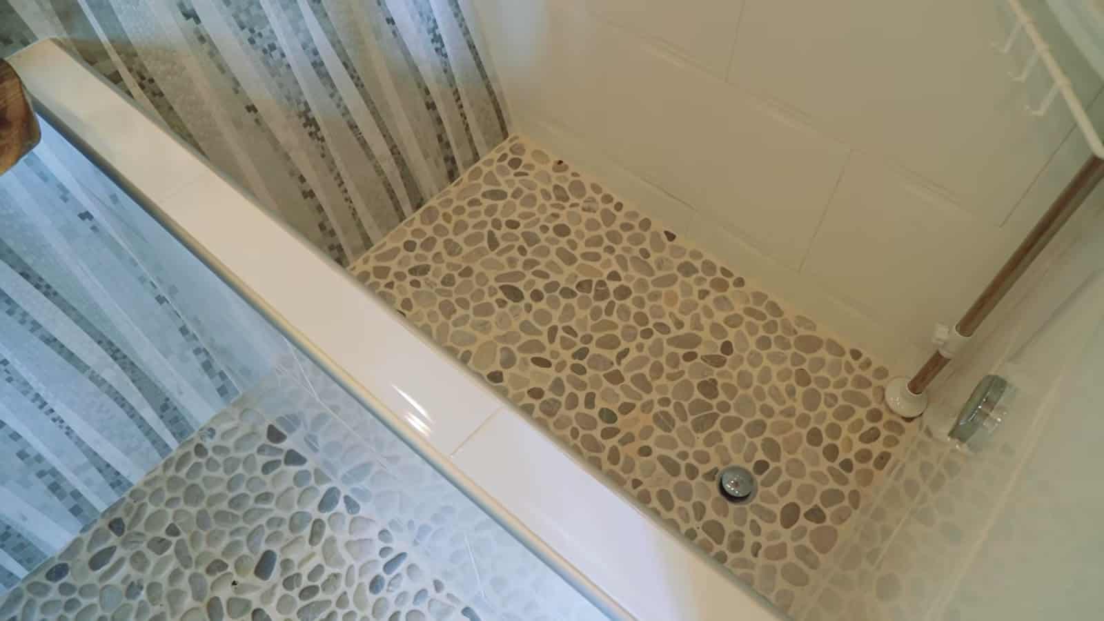 Deep Japanese-style soaking tub with river stone floor and aspen-pattern tile wall