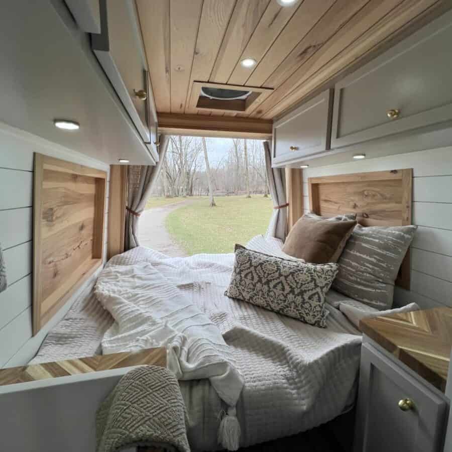 Compact tiny house bedroom with large window and scenic outdoor view.