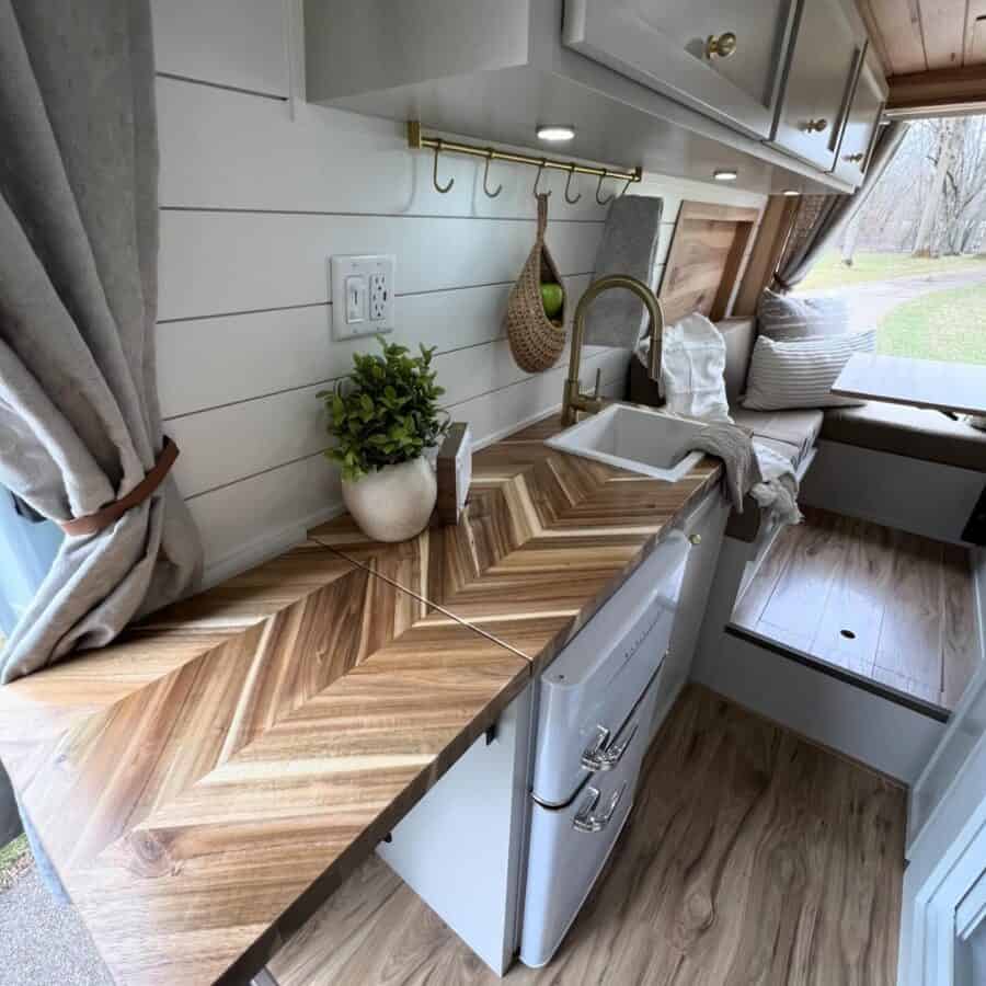 Cozy tiny house kitchen featuring a wooden countertop, sink, and compact storage.