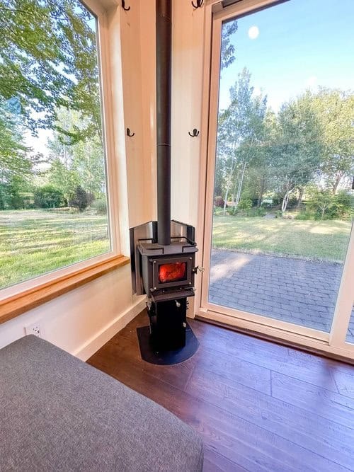 Small Scandinavian tiny house interior with wood stove and large glass doors.