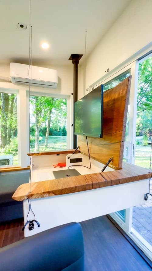 Compact Scandinavian tiny house with a versatile office setup and large windows.