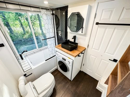 Compact Scandinavian tiny house bathroom with laundry and workspace.