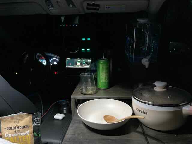 Cozy camper interior with small kitchen essentials and a tablet on the dashboard.