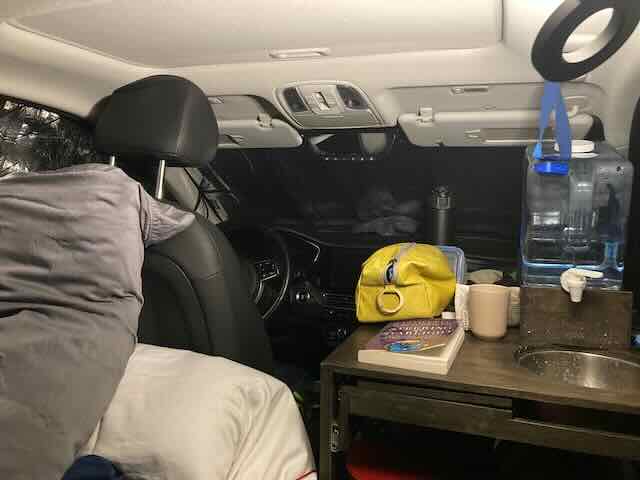 Stealth camper inside a Kia Niro EV with compact living essentials and cozy sleeping area.