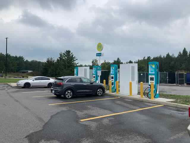 EV charging station with multiple chargers and cars parked nearby.