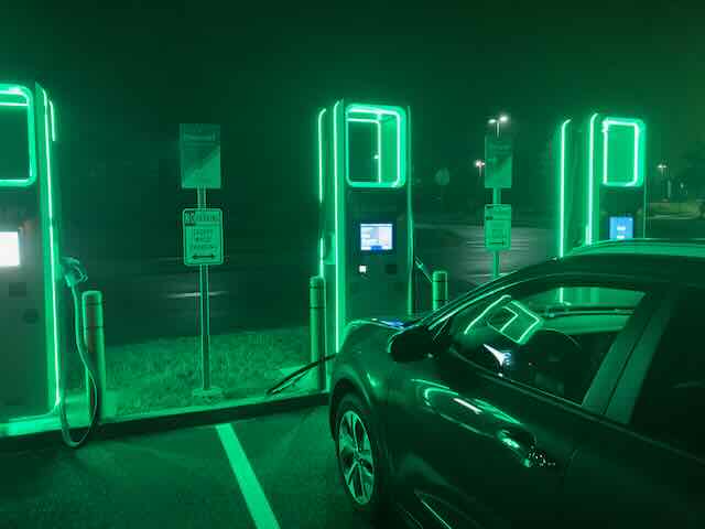 EV charging station with green neon lights at night.