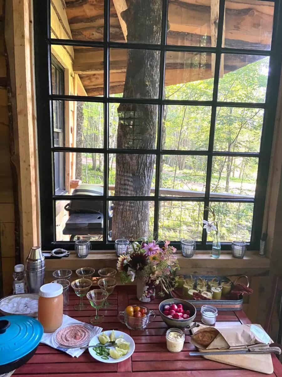 Treehouse kitchen with large window overlooking lush forest and mountain scenery.