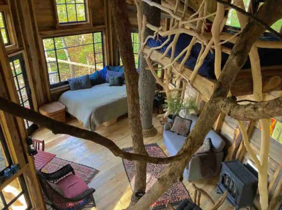 Cozy treehouse interior with sleeping loft and natural wood accents.