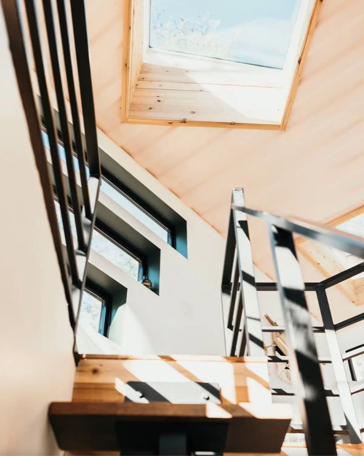 Interior view of a tiny house loft with skylight and wooden accents.