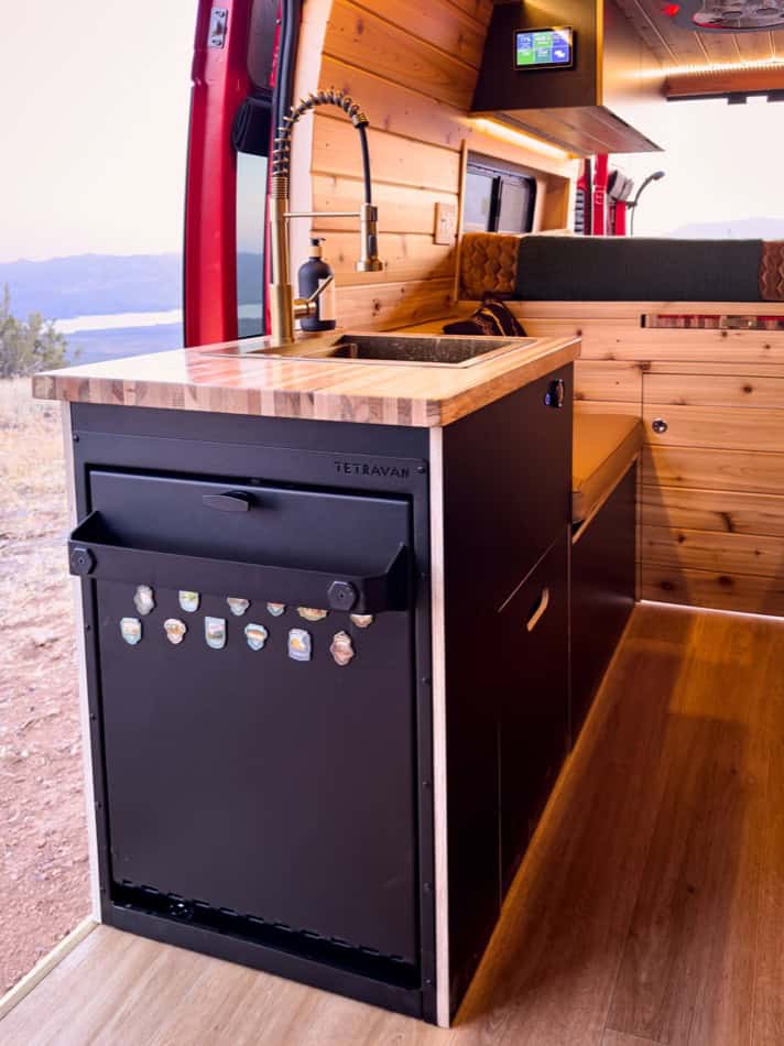 Compact camper van kitchen with wooden accents and modern appliances.