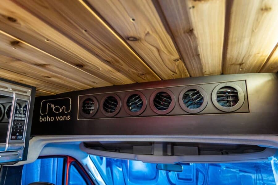 Compact boho van storage with circular vents in a modern camper van interior.