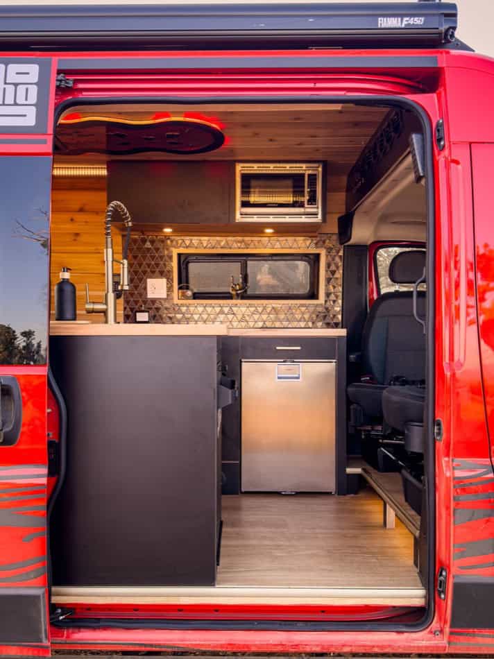 Interior view of a boho-style camper van kitchen and living space.
