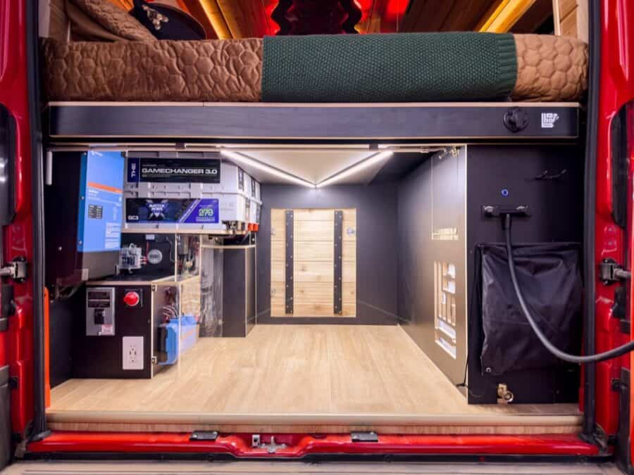 Compact camper van interior with modern tech and cozy sleeping area.