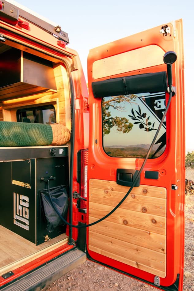 Boho-inspired camper van with wooden accents and outdoor connectivity, perfect for minimalist travel.