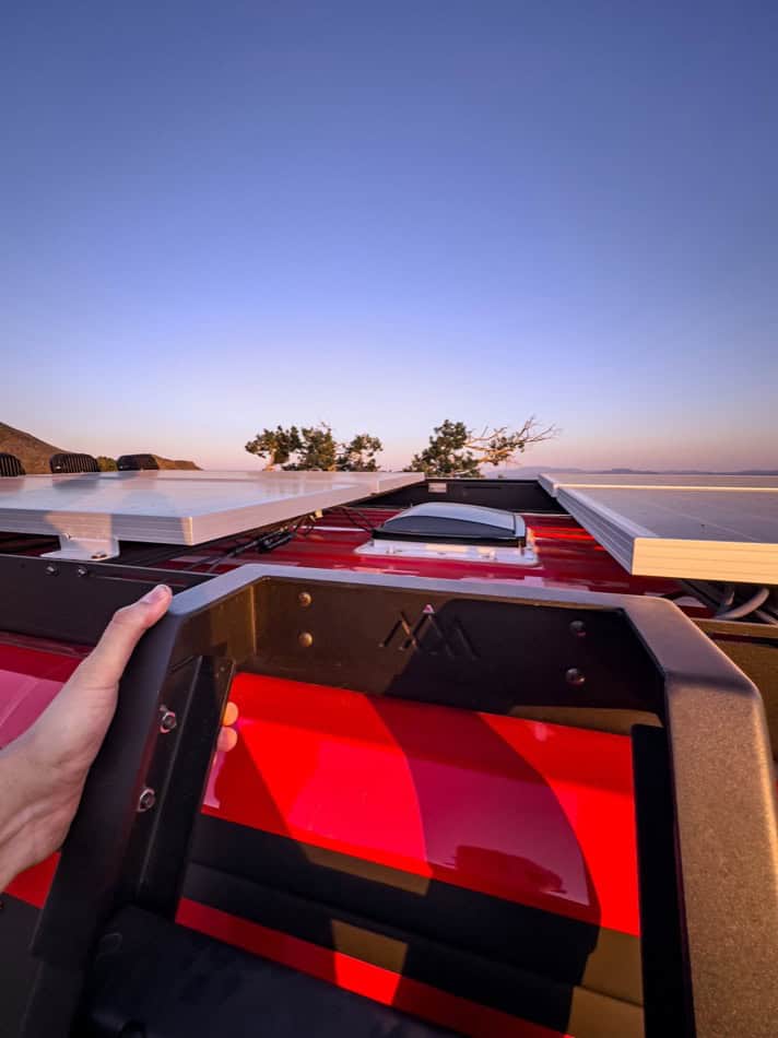 Rooftop solar panels on a tiny house with a scenic water view.