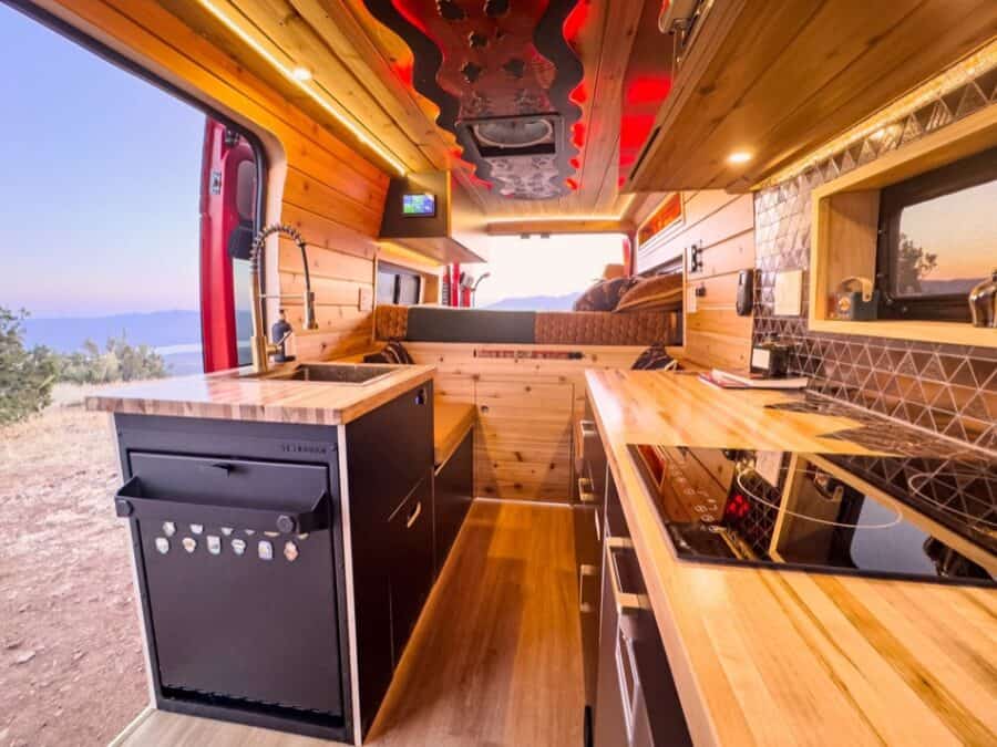 Interior view of a boho-style camper van with wooden accents and compact kitchen setup.