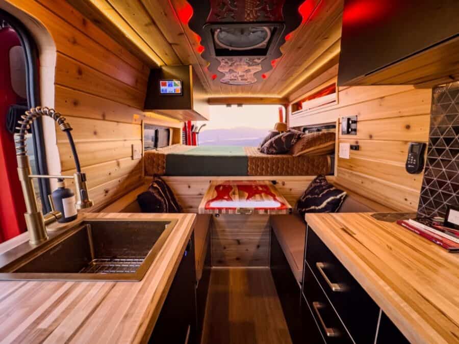 Interior of a modern boho-style camper van with wooden accents and compact living space.