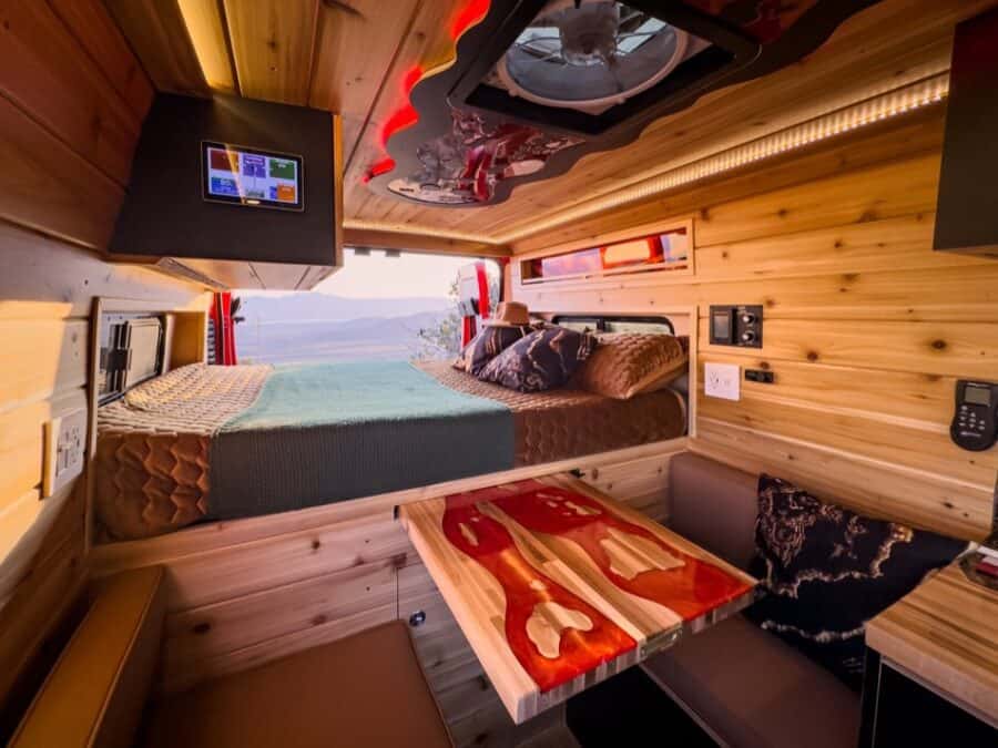 Compact boho camper van interior with cozy bed and modern amenities.