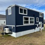 Blue double loft tiny house with modern design and large windows. Perfect for small space living and.