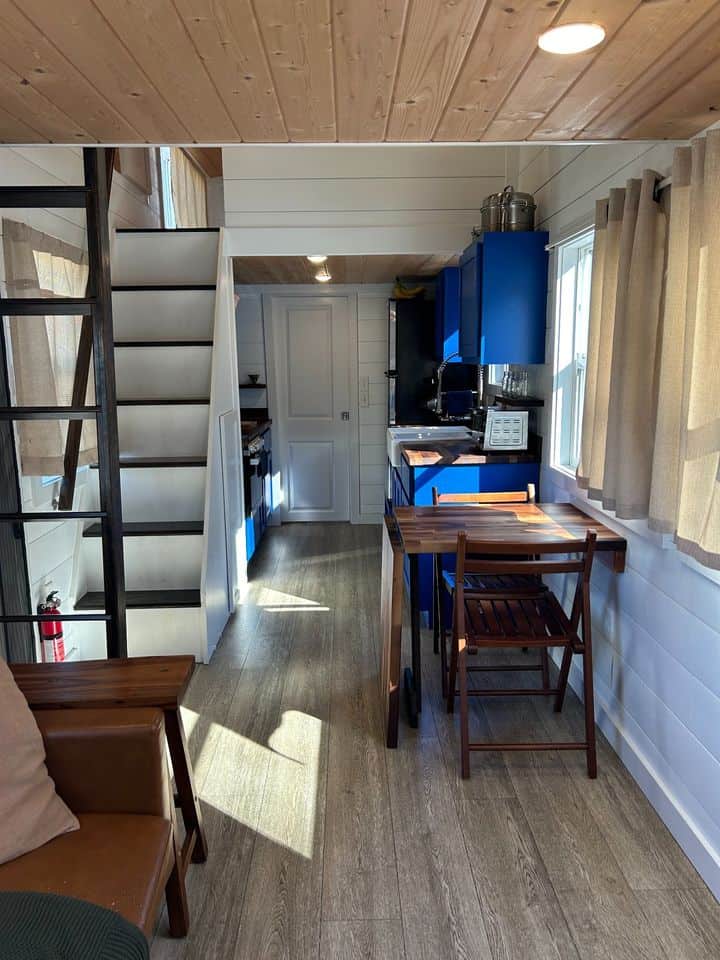 Blue double loft in tiny house with cozy kitchen and dining area.