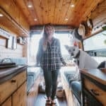 Woman with dog inside a cozy tiny house van conversion, showcasing small space freedom.