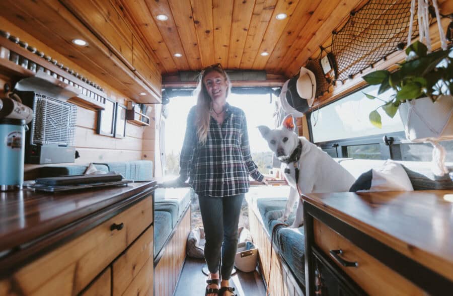 Woman with dog inside a cozy tiny house van conversion, showcasing small space freedom.