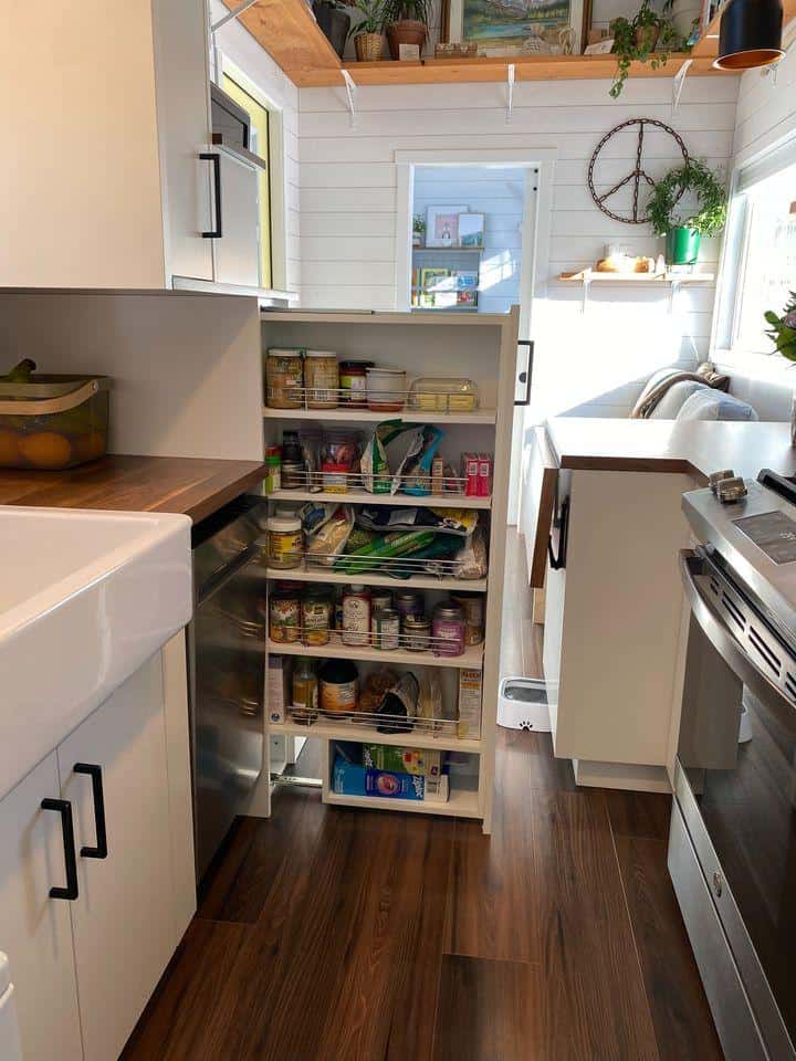 Compact tiny house kitchen with organized pantry and modern appliances.
