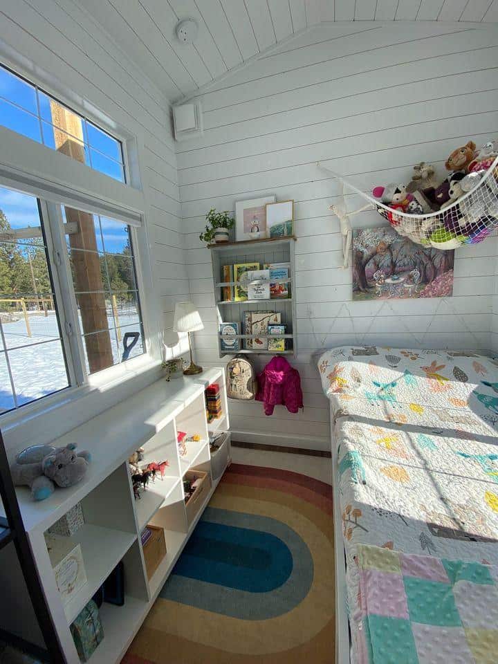 Bright tiny house bedroom with large window and colorful decor.