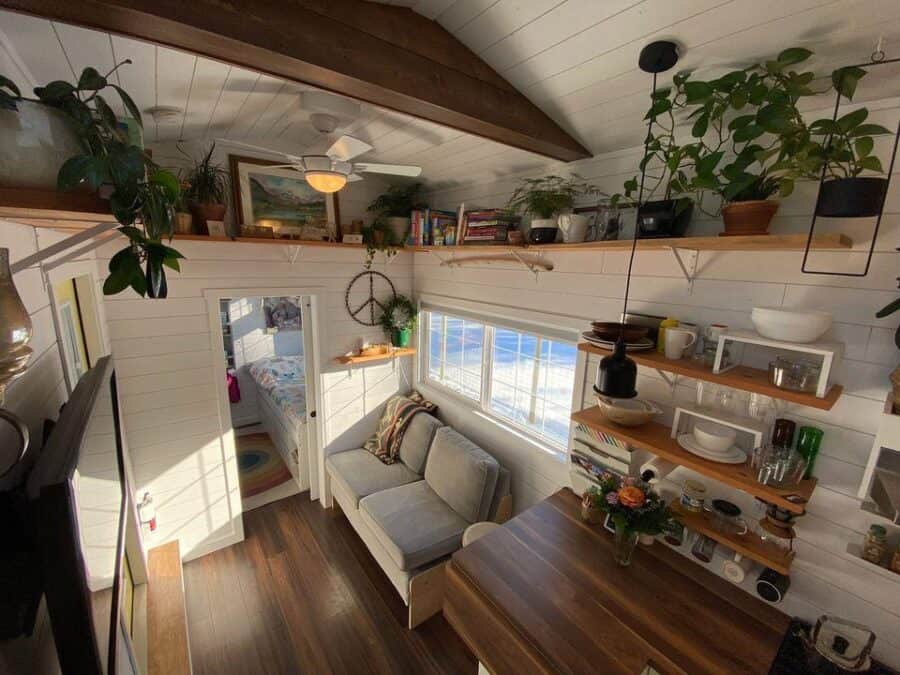 Bright tiny house interior with cozy seating and natural light in a Kootenay, BC community.