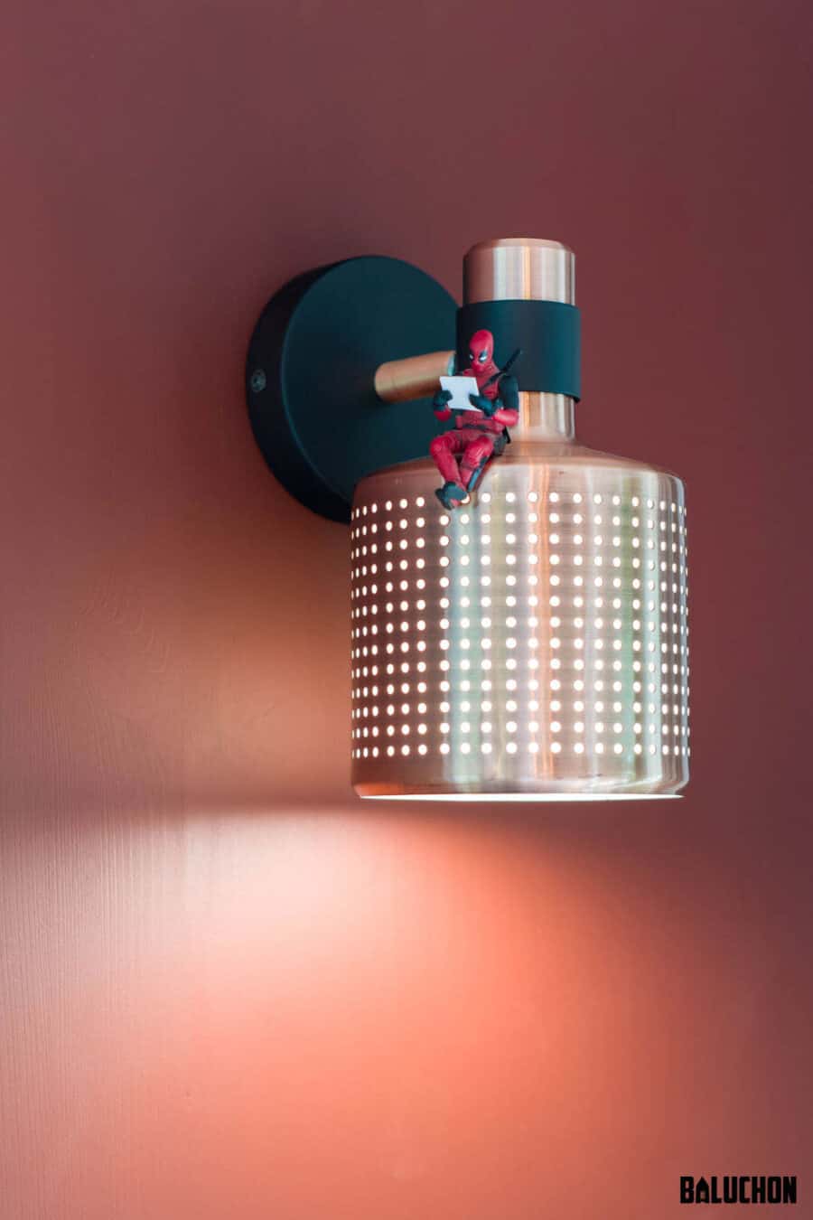 Wall-mounted light fixture with a modern design and small figurine decoration.