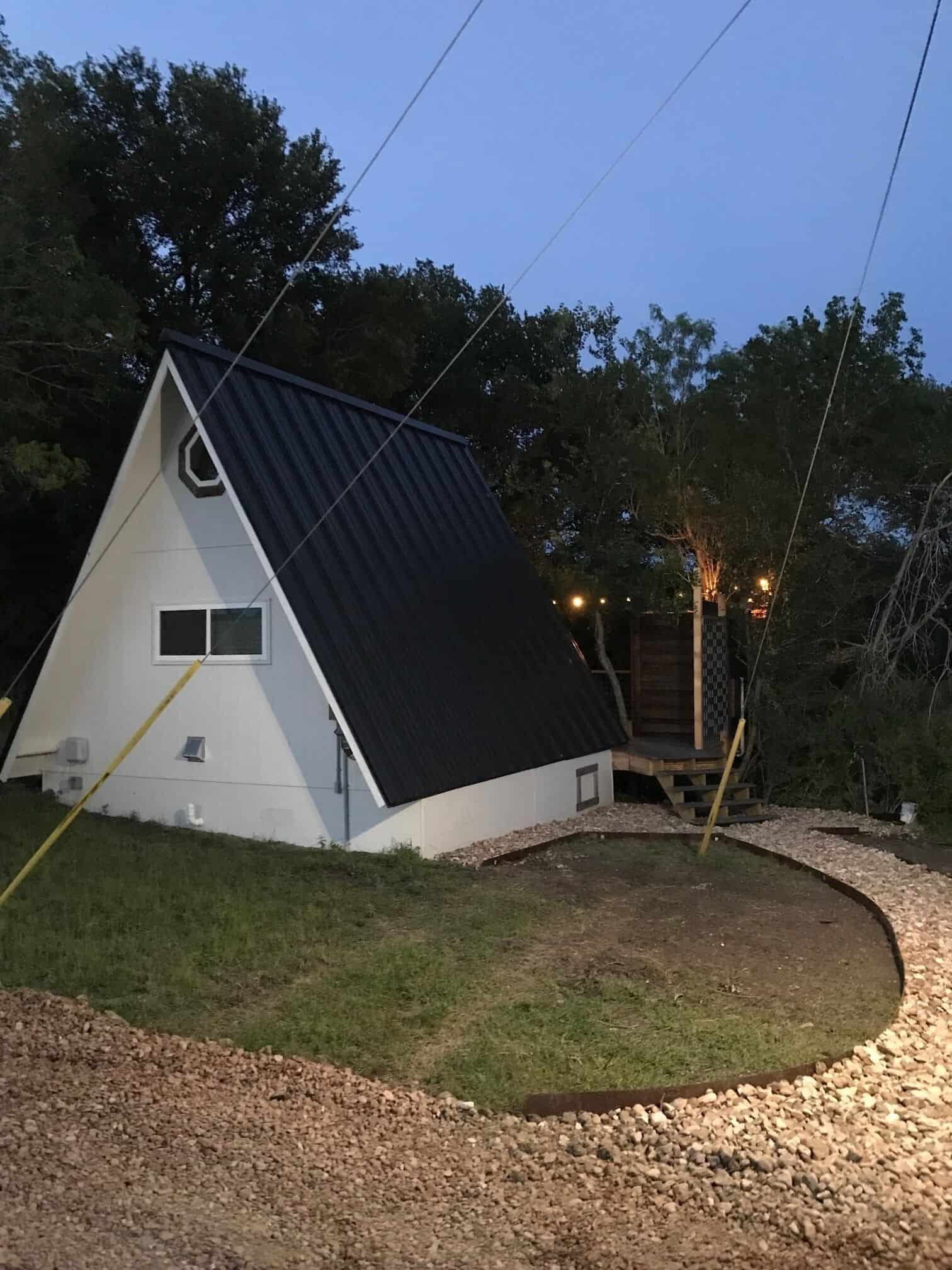 The Cabin at Spencer Ranch A-frame at dusk with glowing string lights on deck