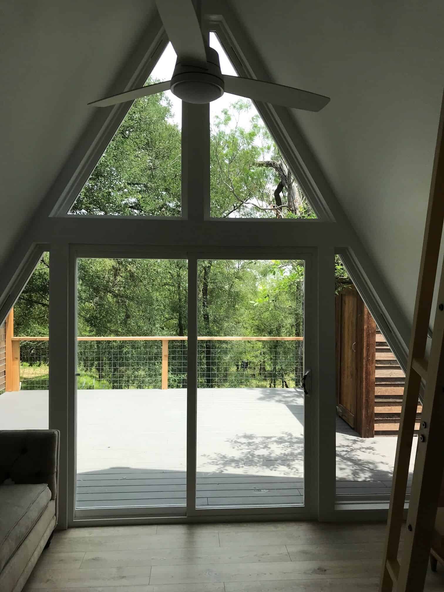 Floor-to-ceiling A-frame windows with view to trees and deck at Spencer Ranch cabin