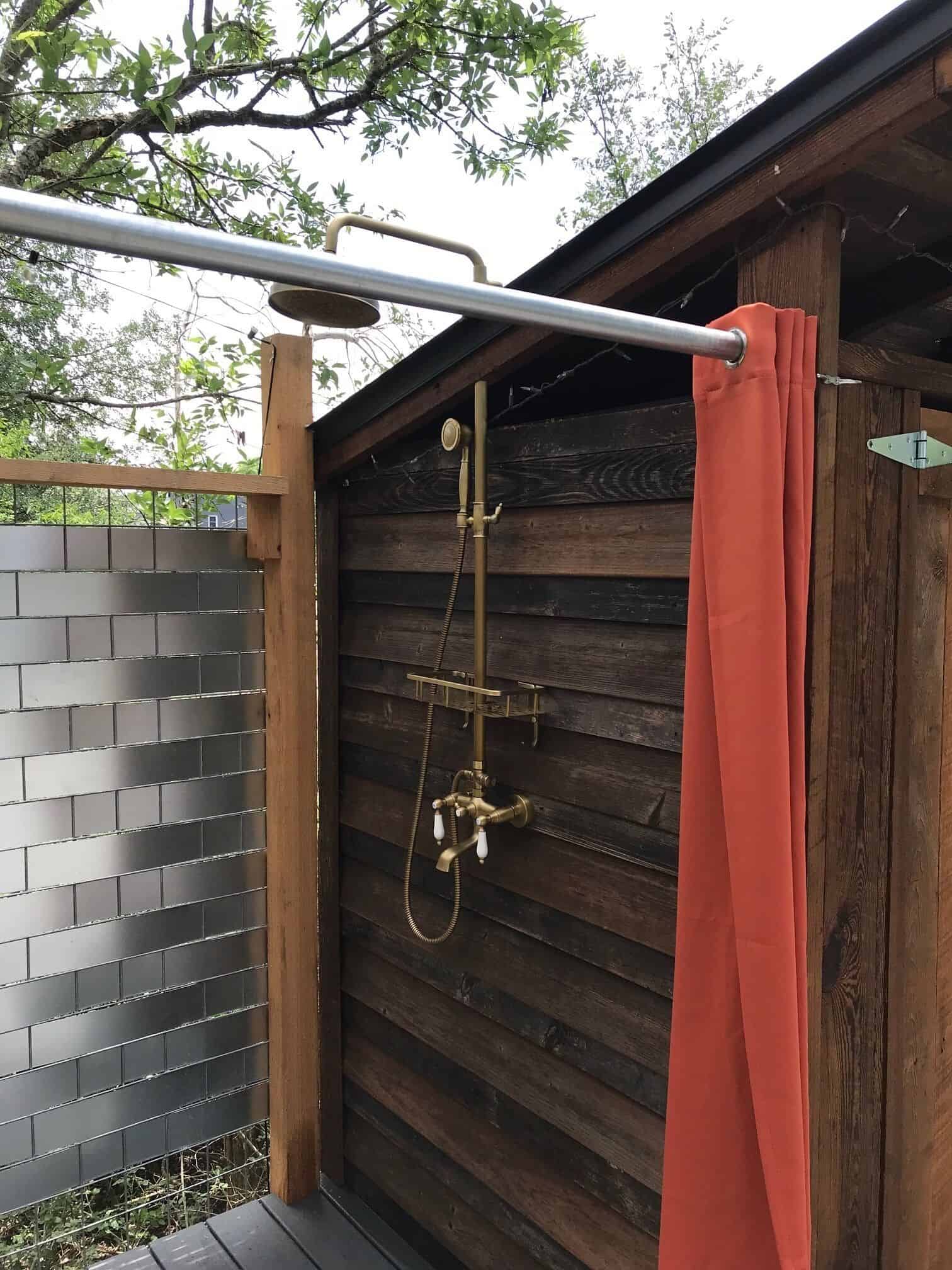 Brass rainfall shower fixtures on reclaimed wood wall at Spencer Ranch outdoor shower