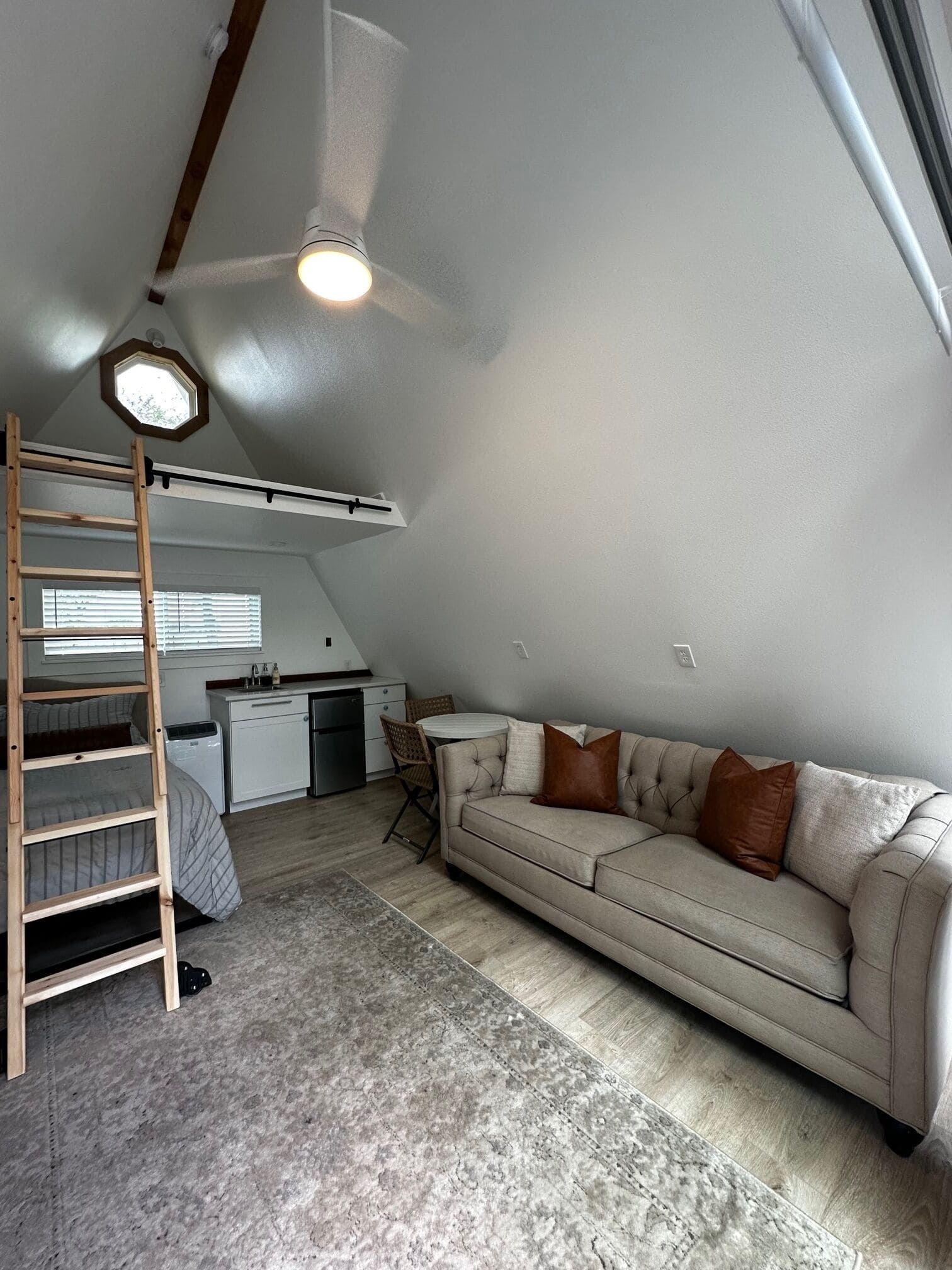 Full interior view of Spencer Ranch A-frame showing couch, loft ladder, bed, and kitchenette